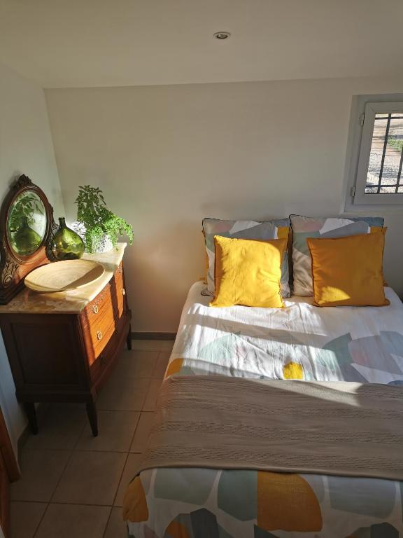 Un dormitorio con una cama con almohadas amarillas y una mesa. en Studio de charme en Provence en Le Luc