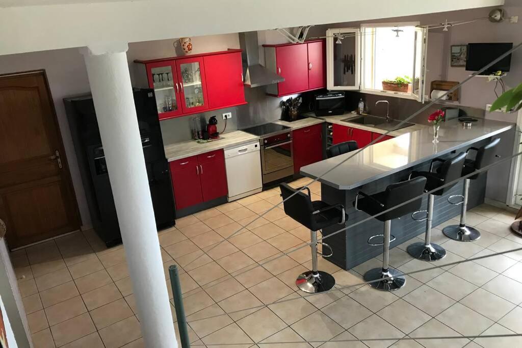 - une cuisine avec des placards rouges et une grande île dans l'établissement Maison spacieuse, à Gruissan