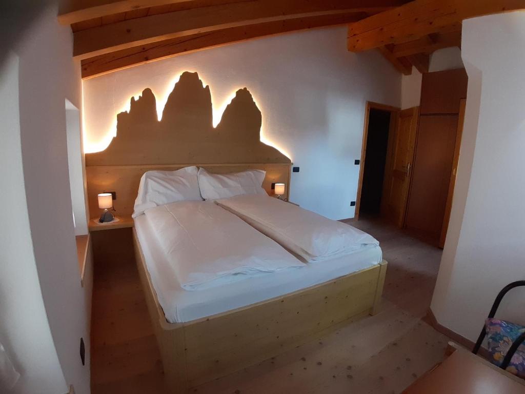 a bedroom with a bed with a wooden headboard at Appartamento 3cime Stefania in Padola