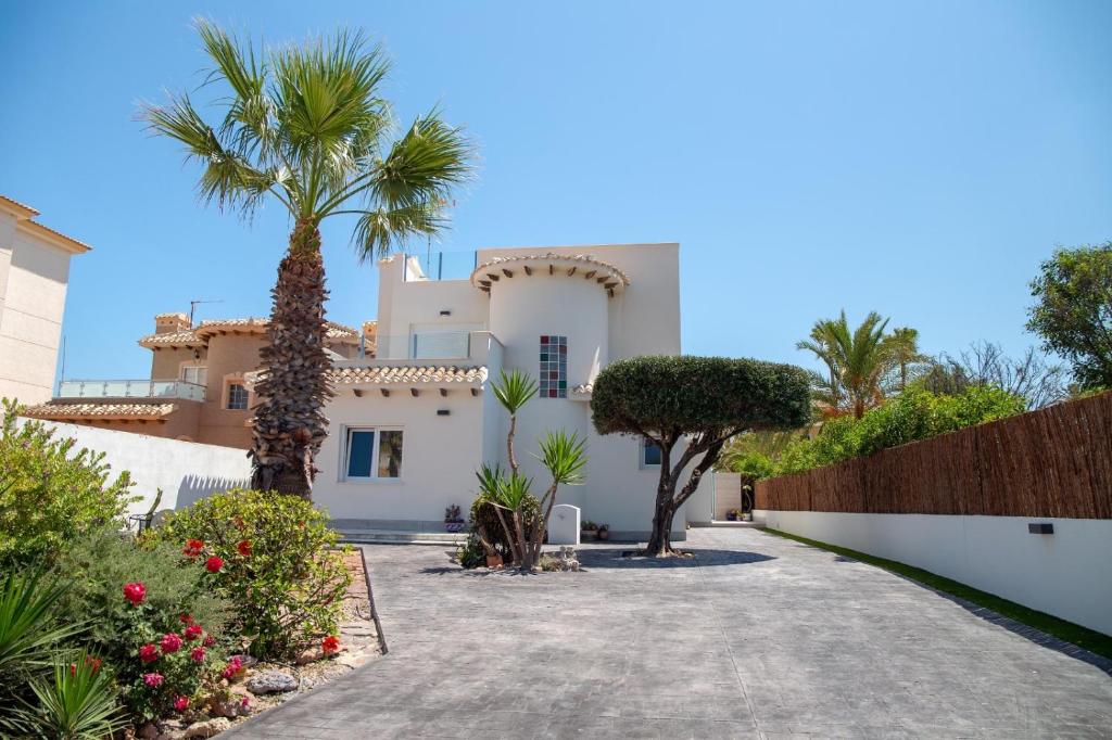 a house with palm trees and a driveway at Beach Villa Flamenca in Orihuela
