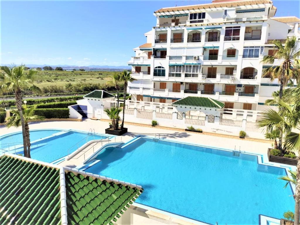 ein Apartment mit einem Pool vor einem Gebäude in der Unterkunft Eldorado Apartment La Mata in La Mata