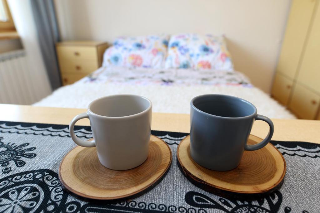 dwa kubki kawy siedzące na stole z łóżkiem w obiekcie Pokoje u flisaka w Krościenku