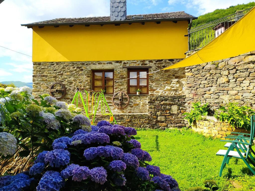 einen Garten mit lila Blumen vor einem Gebäude in der Unterkunft La Cabana´l Cachican in Cangas del Narcea