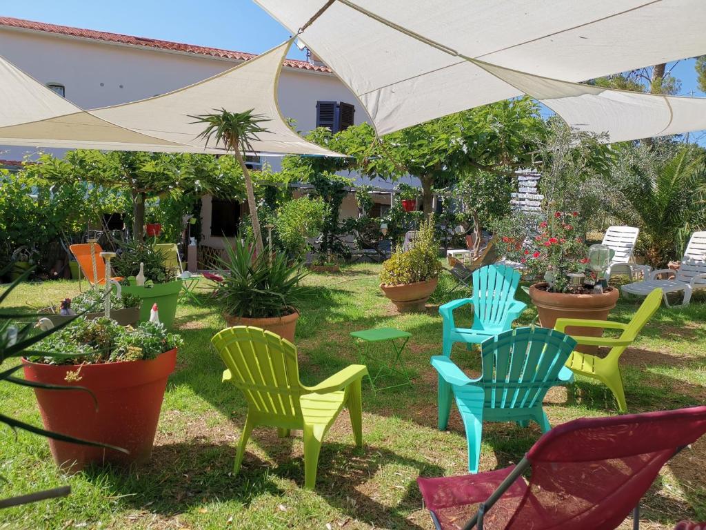 een groep stoelen en een paraplu in een tuin bij Hotel & Appartements Punta e Mare in Cargèse
