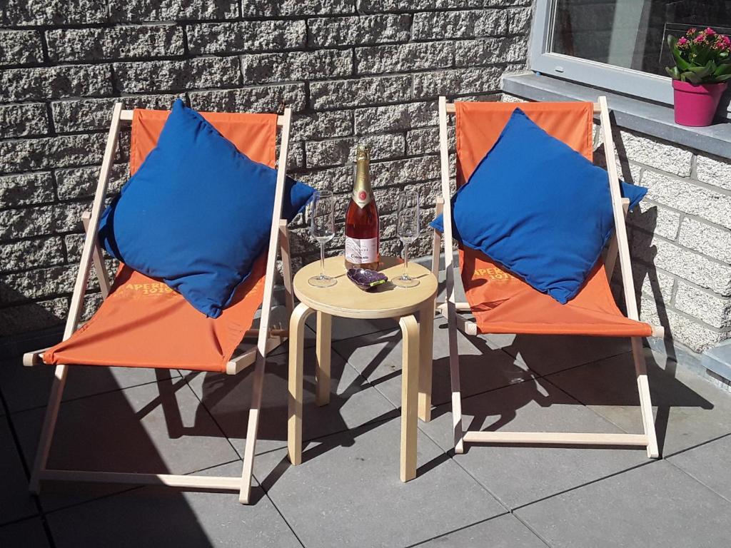 2 Stühle und ein Tisch mit einer Flasche Bier in der Unterkunft Terrasses de Malmedy - Duplex 419 in Malmedy