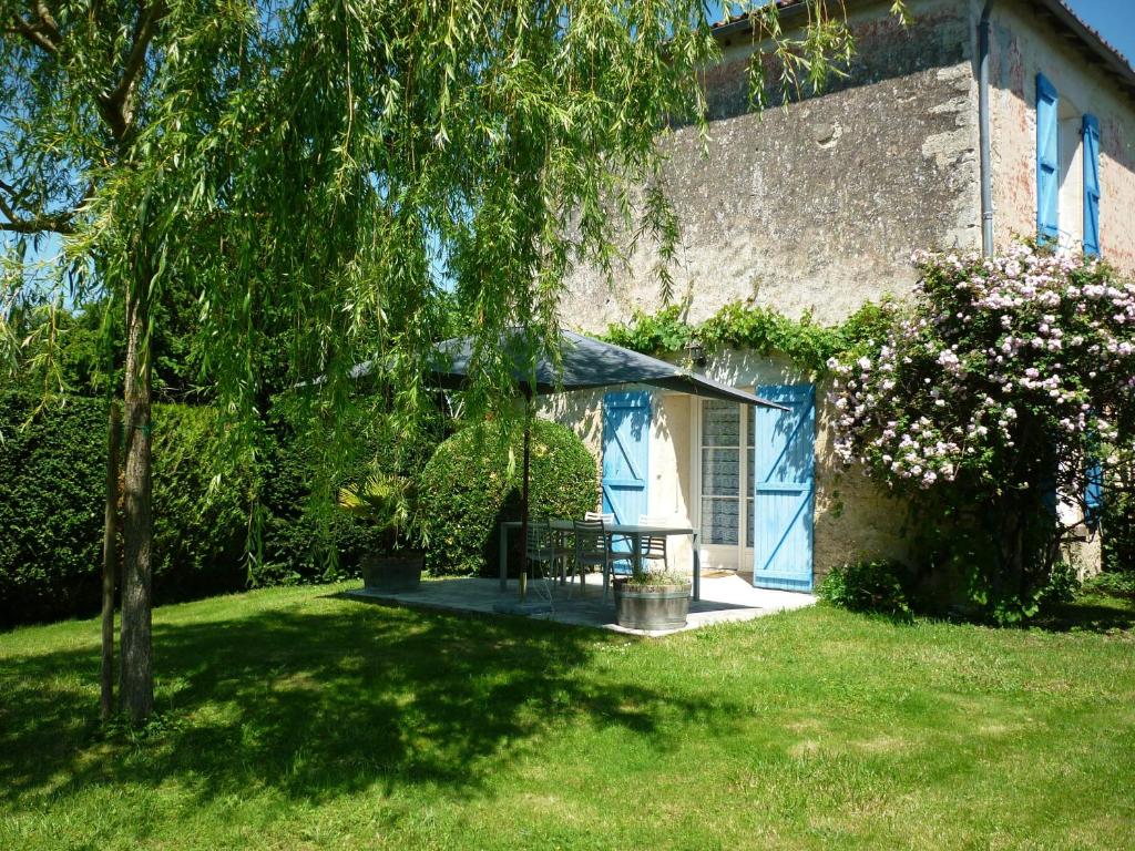 a house with a blue door in a yard at Gîte Le Logis de Faugerit in Frontenay-Rohan-Rohan