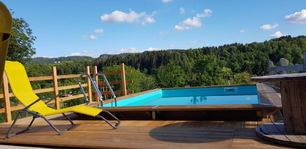une piscine avec un toboggan et une chaise sur une terrasse dans l'établissement Le Jura en toutes saisons piscine, SPA, climatisation, balades 2cv, à Bonlieu
