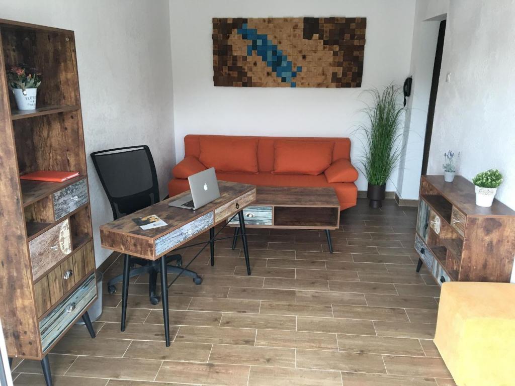 a living room with an orange couch and a desk with a laptop at Cazare For-Rest Accommodation in Baraolt