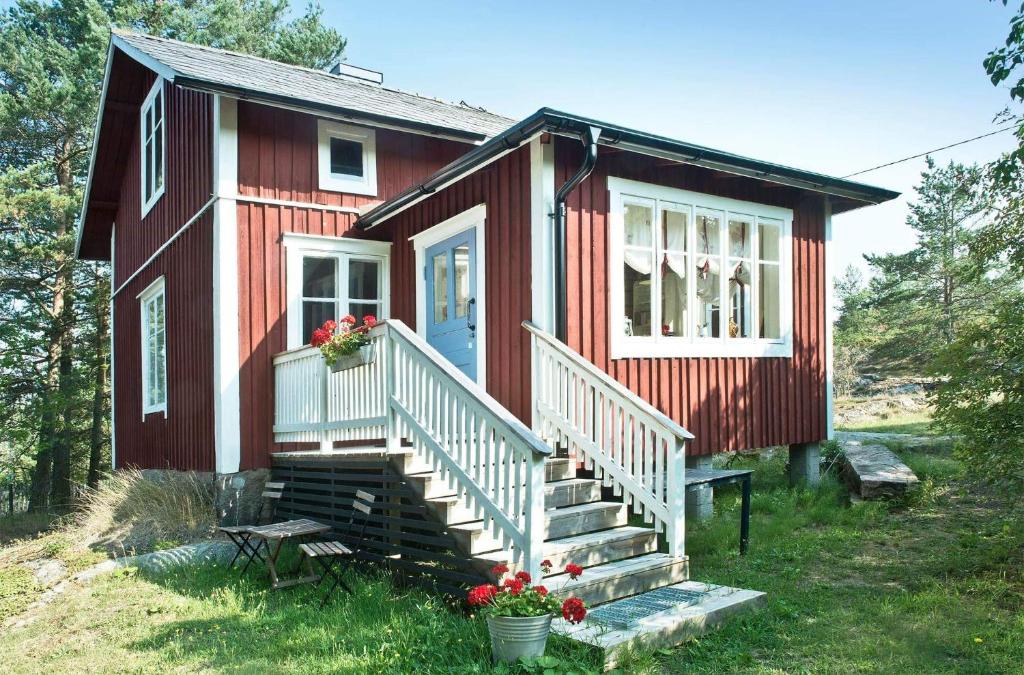 a small red house with stairs and a porch at Hannaksen tila in Korppoo