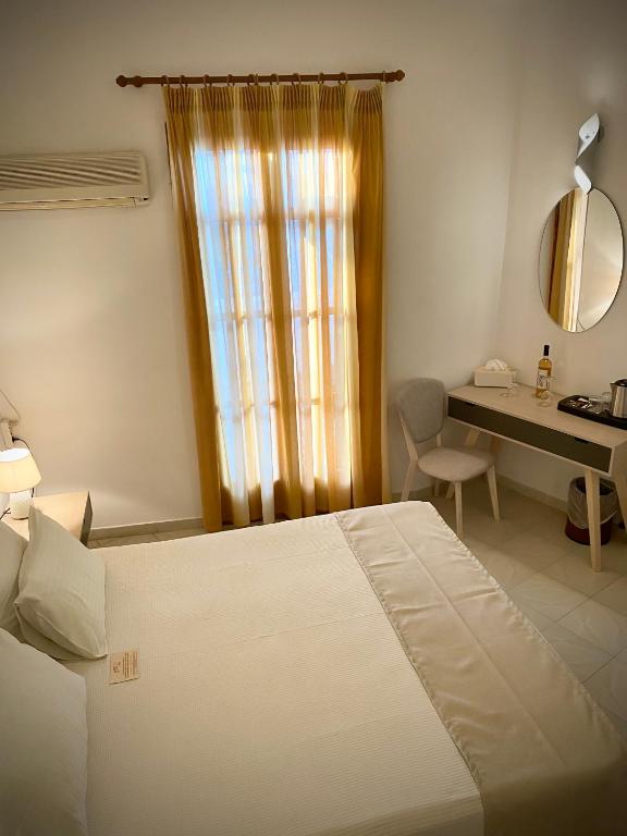 a bedroom with a bed and a desk and a window at Asteri Hotel in Livadi