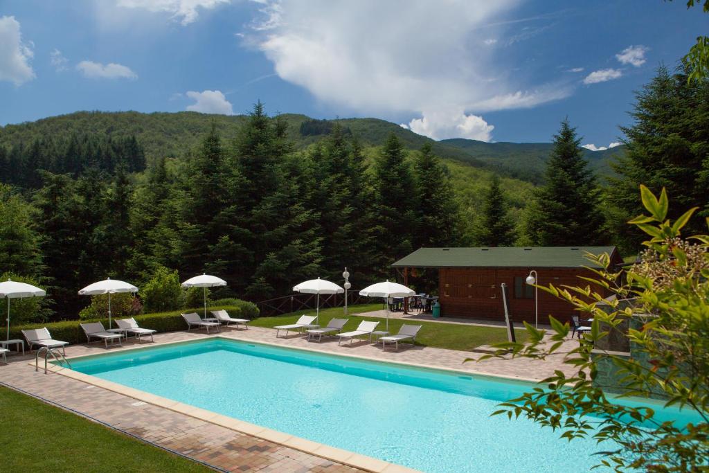 una piscina con sillas y sombrillas y un edificio en Il Borgo Dei Corsi - Charming Holiday Apartments en Ortignano Raggiolo