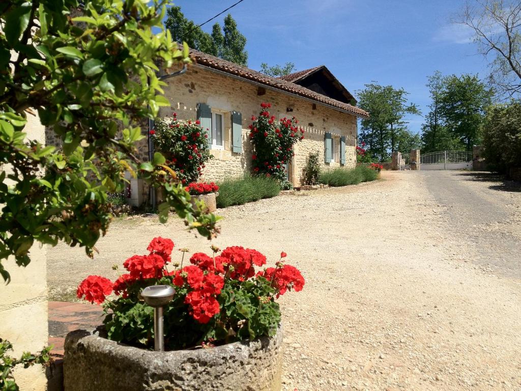 uma casa com flores vermelhas ao lado de uma estrada em Chambres d’hôtes de Pouzatel em Fumel