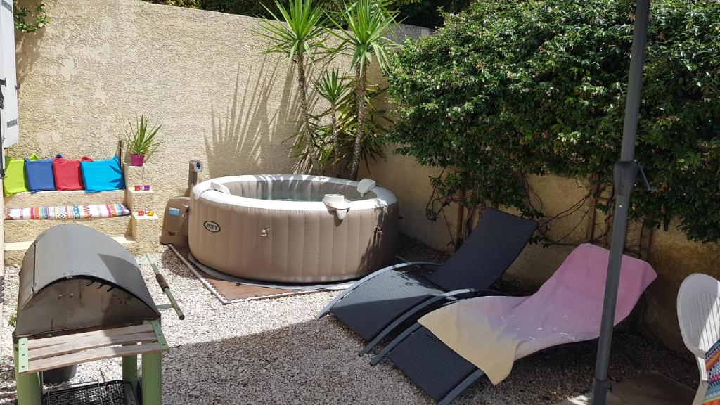 a hot tub and a chair in a garden at Petite maison au calme garrigue et mer Montpellier in Teyran