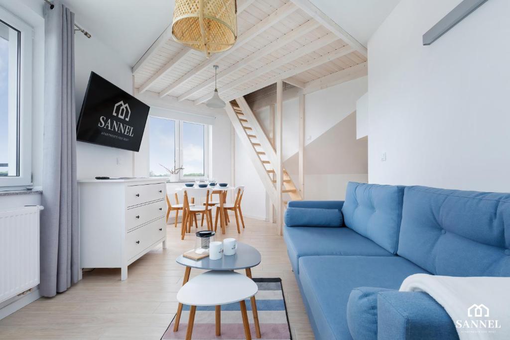 een woonkamer met een blauwe bank en een tafel bij Apartament BALTIC PANORAMA in Dziwnówek
