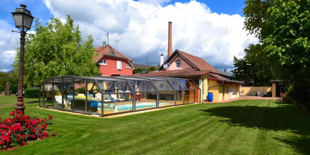 una casa con un invernadero de cristal en un patio en Gîte Oncle Yerry, en Ostheim