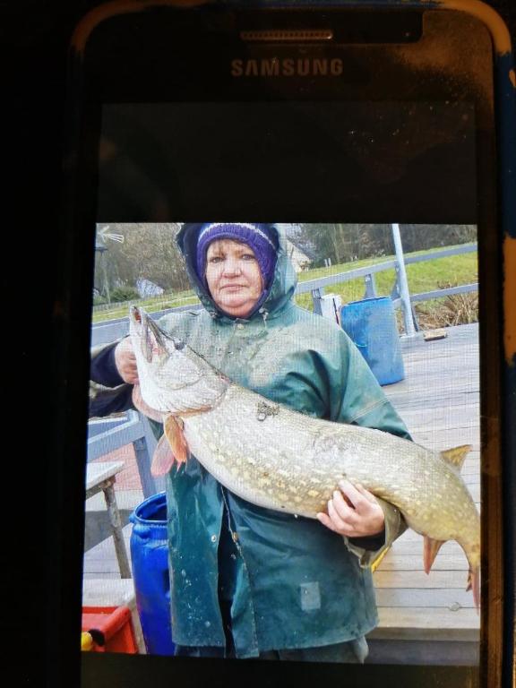 a woman holding a fish on a cell phone at Cicha Przystań in Nowy Dwór Gdański