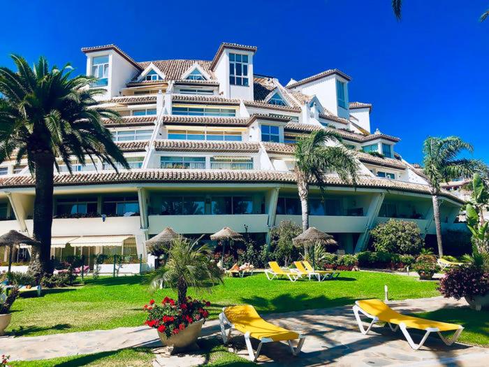 duży hotel z krzesłami i palmami przed nim w obiekcie Parque Miraflores Nr. 218. Tennis & South-west seawiew w mieście Mijas Costa