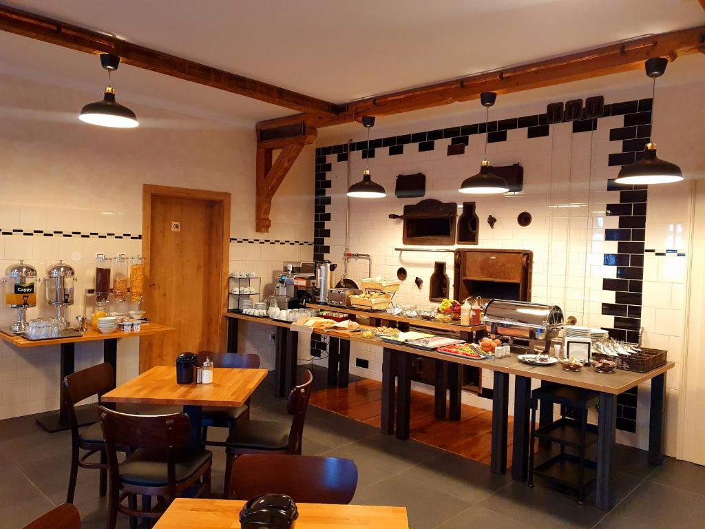 a large kitchen with tables and chairs in a restaurant at Hotel KORTUS in Jetřichovice