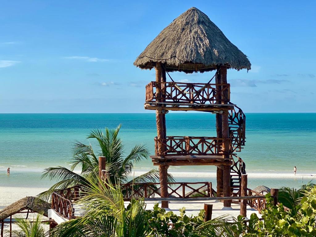 uma grande torre de madeira numa praia com o oceano em Palapas del Sol em Ilha Holbox