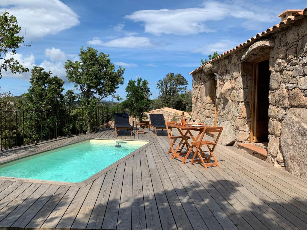 un patio con mesa y sillas y una piscina en ALZITEDDA, en Porto Vecchio