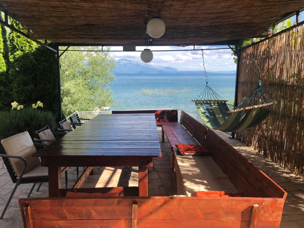 a wooden table and hammock on a patio with the ocean at Villa Elen Kamen in Struga