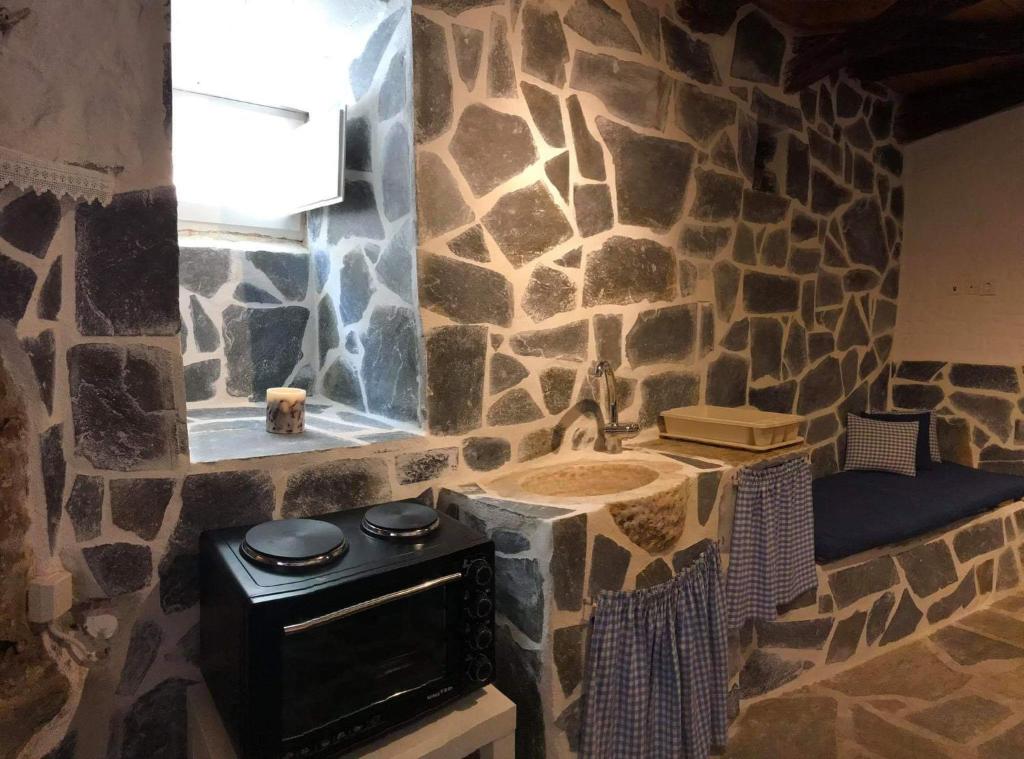 - une cuisine aux murs en pierre avec une cuisinière et un évier dans l'établissement Angelica, à Áno Sýros