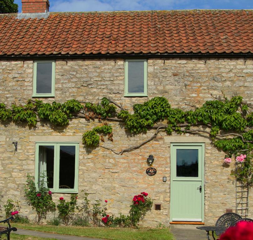 a stone house with a green door and windows at Riccal Dale Cottage in Helmsley