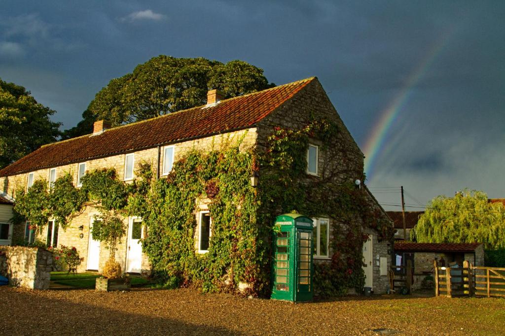 een huis bedekt met klimop met een groene telefoon bij Kirkdale Cottage in Helmsley