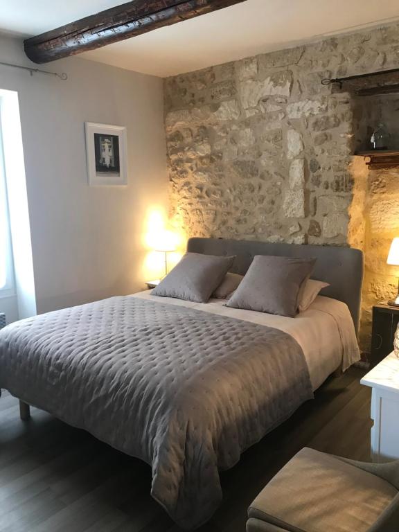 ein Schlafzimmer mit einem großen Bett und einer Steinmauer in der Unterkunft Au cœur de Céreste in Céreste