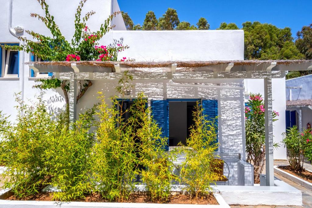 a white house with flowers on the facade at Coralli Seaside Resort in Livadakia