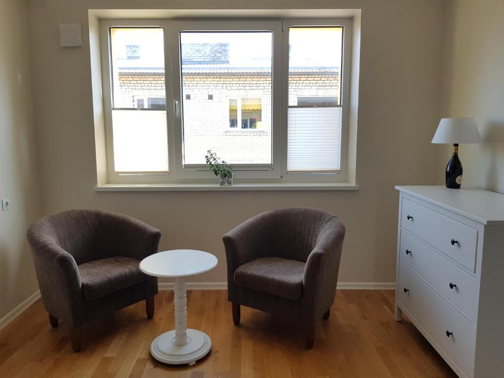 2 stoelen en een tafel in een kamer met een raam bij Aia Apartment in Haapsalu
