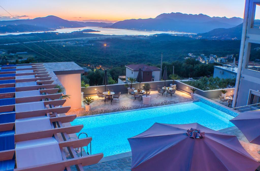 a pool on top of a building with tables and umbrellas at Apartments Villa Preciosa in Kotor