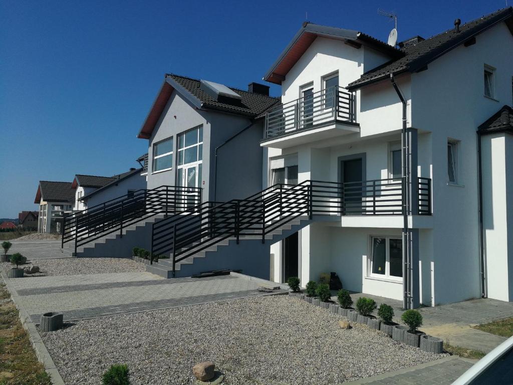 Una casa blanca con escaleras al costado. en Apartamenty "Marynarska " Rusinowo, en Rusinowo