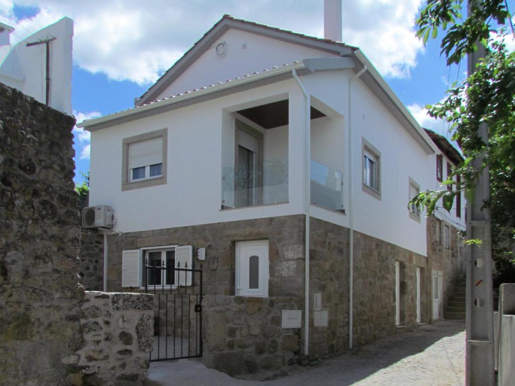 duży biały dom z kamienną ścianą w obiekcie Casa das Nações w mieście Donas