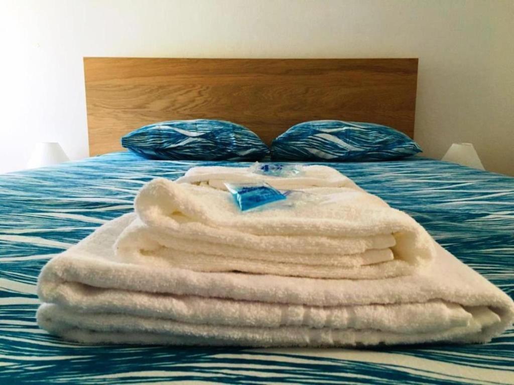 una pila de toallas sentadas encima de una cama en SwordFish Holiday Home, en Peniche