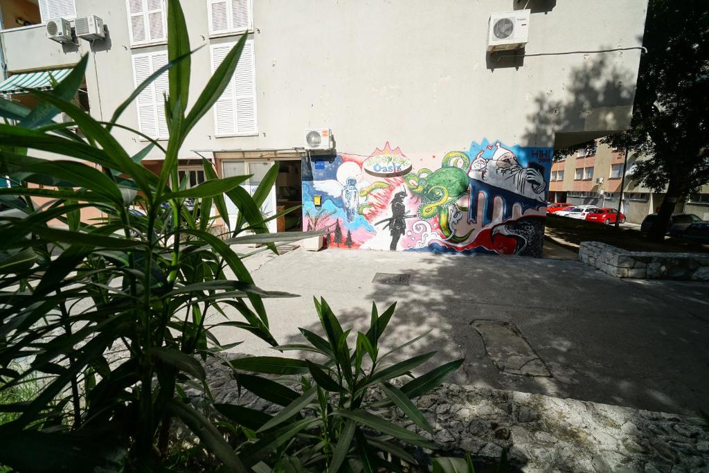 un mur orné d'une fresque murale avec une plante dans l'établissement Oasis hostel, à Split