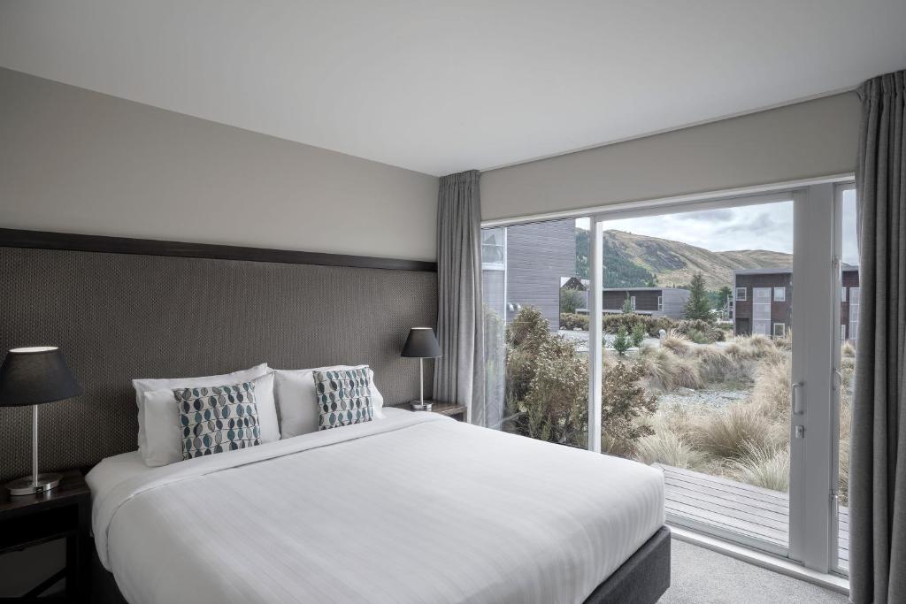a bedroom with a large bed and a large window at Peppers Bluewater Resort in Lake Tekapo