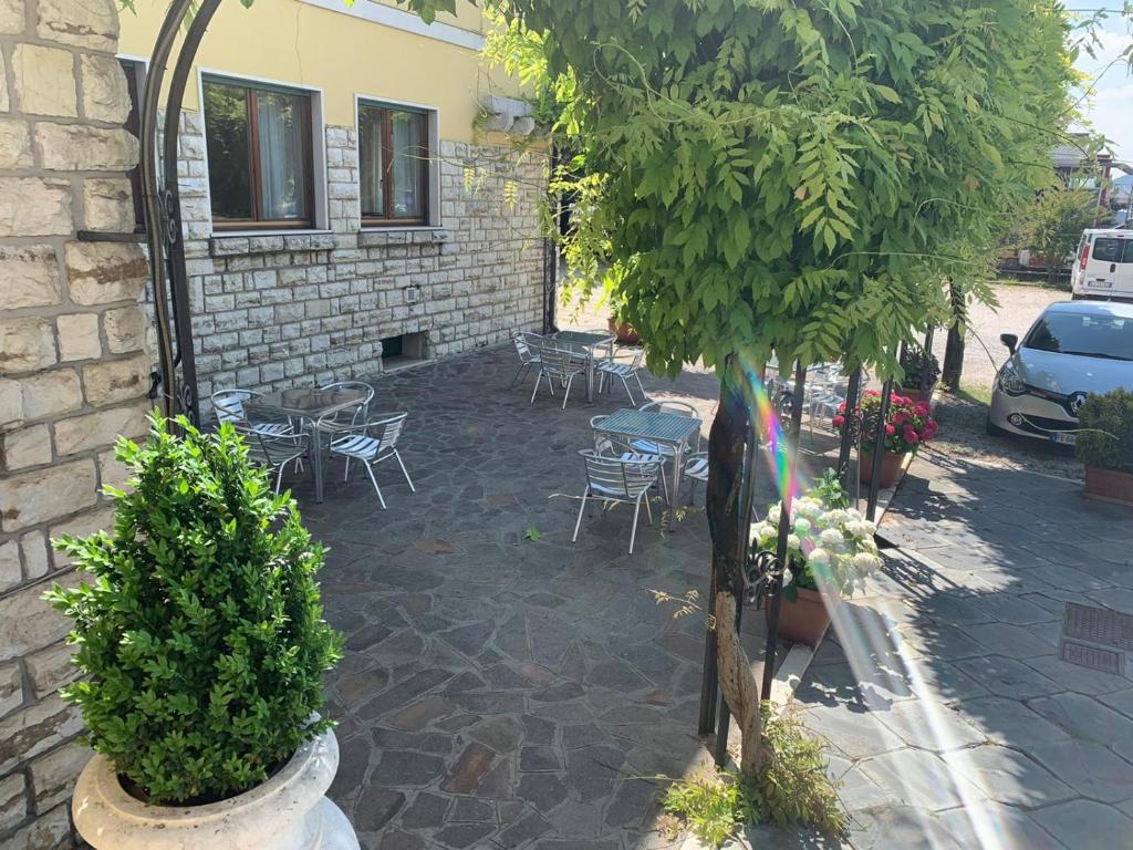 eine Terrasse mit Stühlen, Tischen und einem Baum in der Unterkunft La Pina in Rezzato