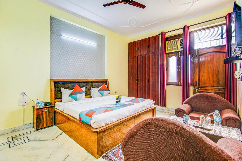 een slaapkamer met een bed en 2 stoelen bij FabExpress Royal Ashray in Noida