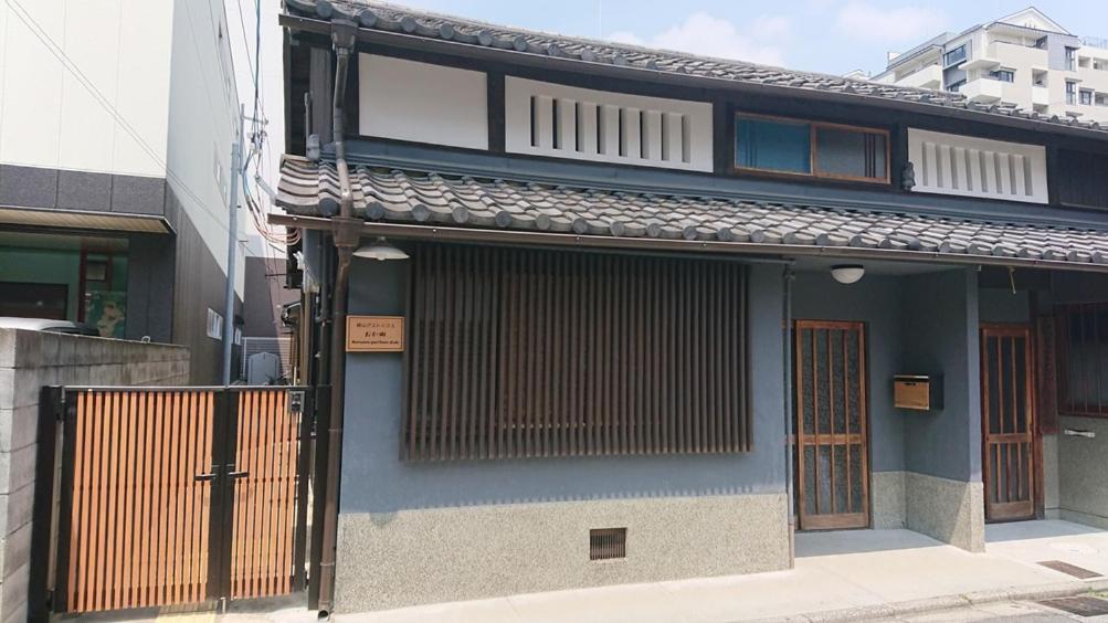 un bâtiment bleu avec un portail sur son côté dans l'établissement 桃山ゲストハウス おかだ, à Kyoto