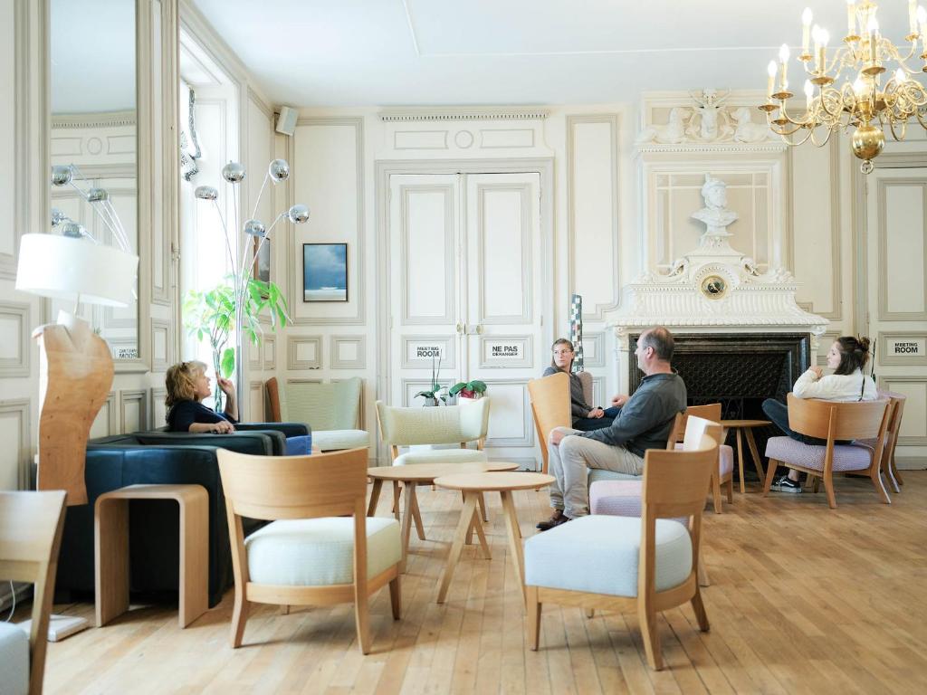 a group of people sitting in a room with a fireplace at Logis Hôtel de l'Europe in Poitiers