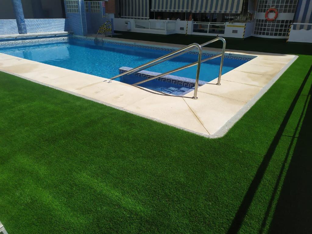 フエンヒロラにあるFenix con piscina y terrrazaの緑の芝生が広がるスイミングプール