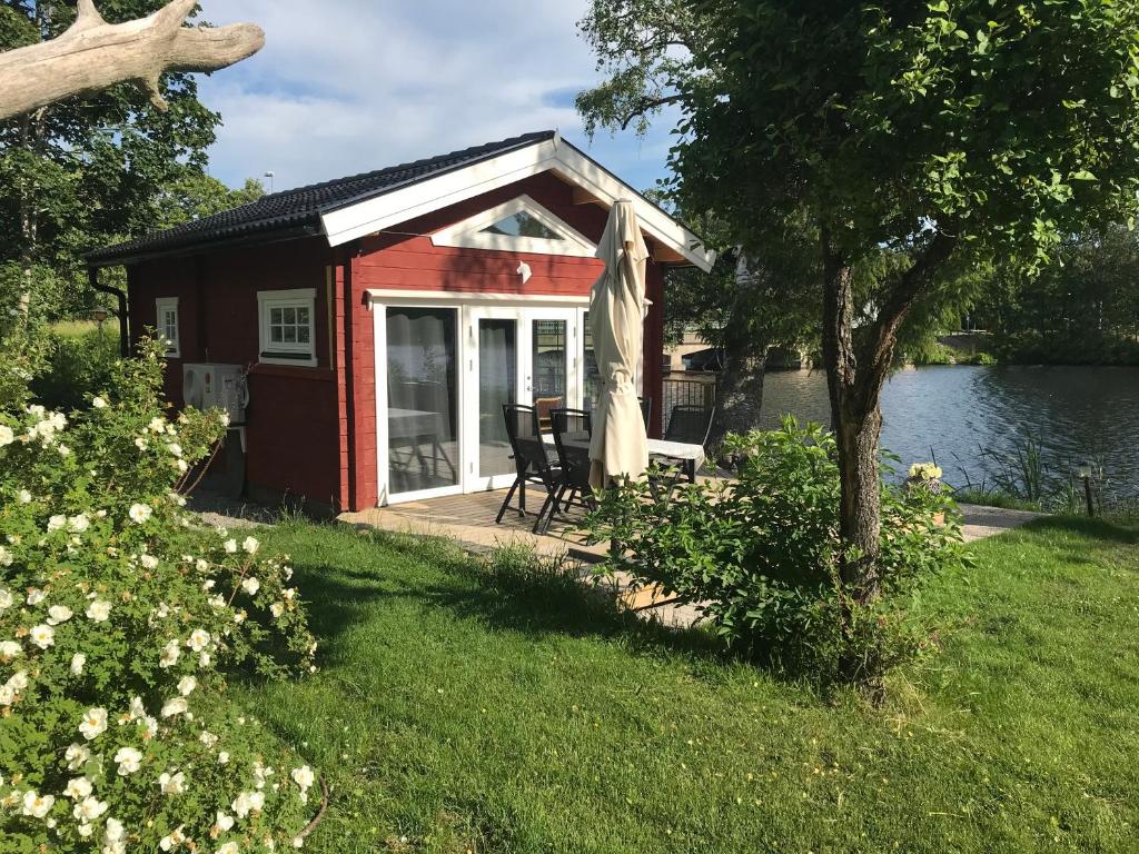 a red cottage with a deck and a lake at Lottas stuga in Smedjebacken