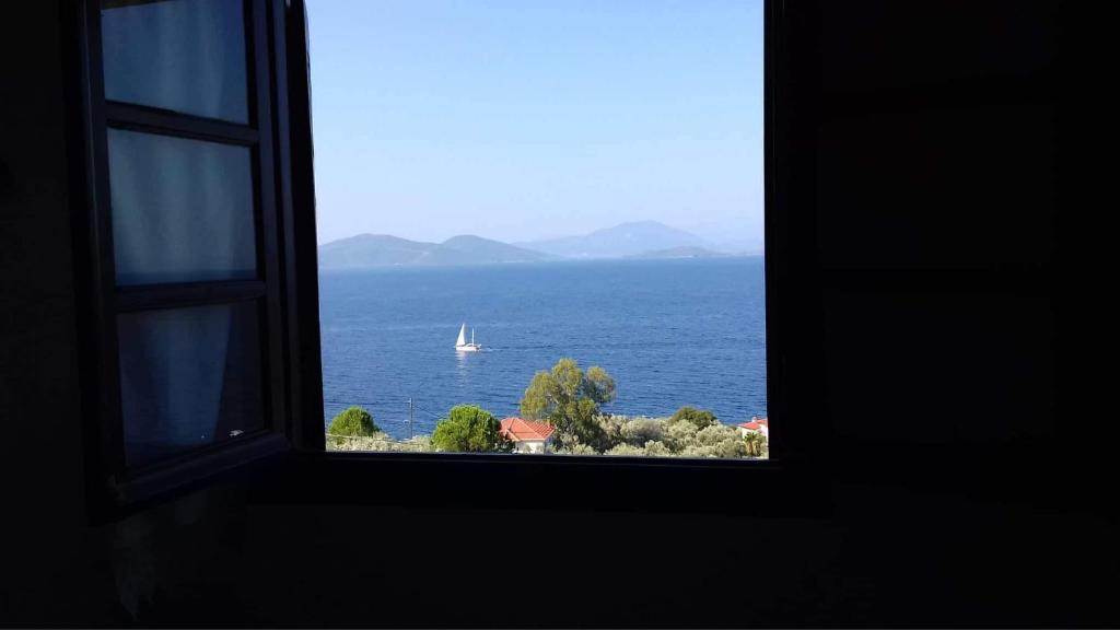a window with a view of a sailboat in the ocean at Villa Belian 2 in Argalasti