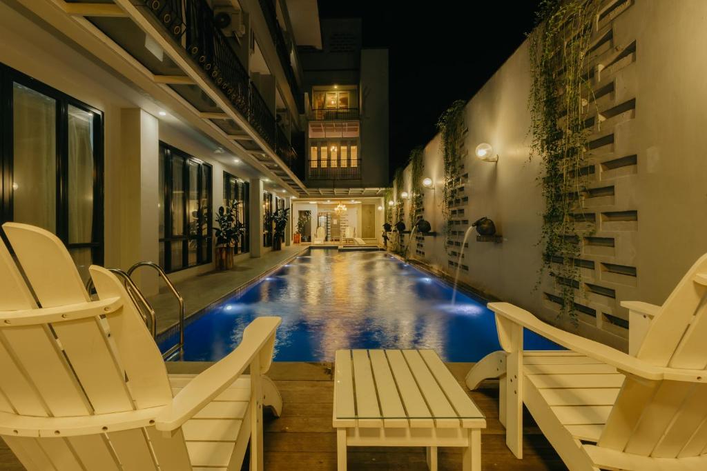 a swimming pool in a building with two chairs at Urbanest Inn House TB Simatupang in Jakarta