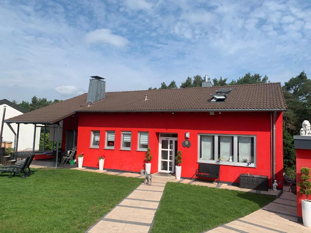 una casa roja con un perro delante de ella en Ferienwohnung Familie Schott, en Schwaig