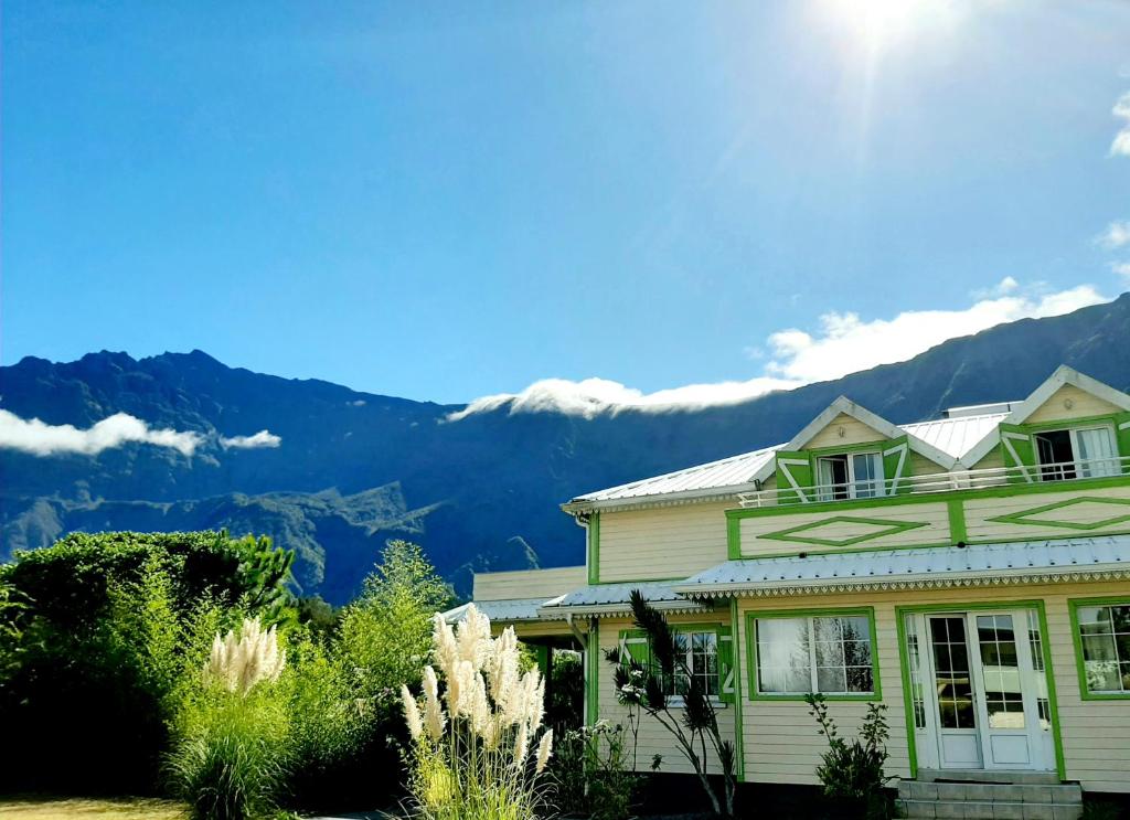 una casa verde con montañas en el fondo en Chambres d'hôtes DORIS, en Cilaos