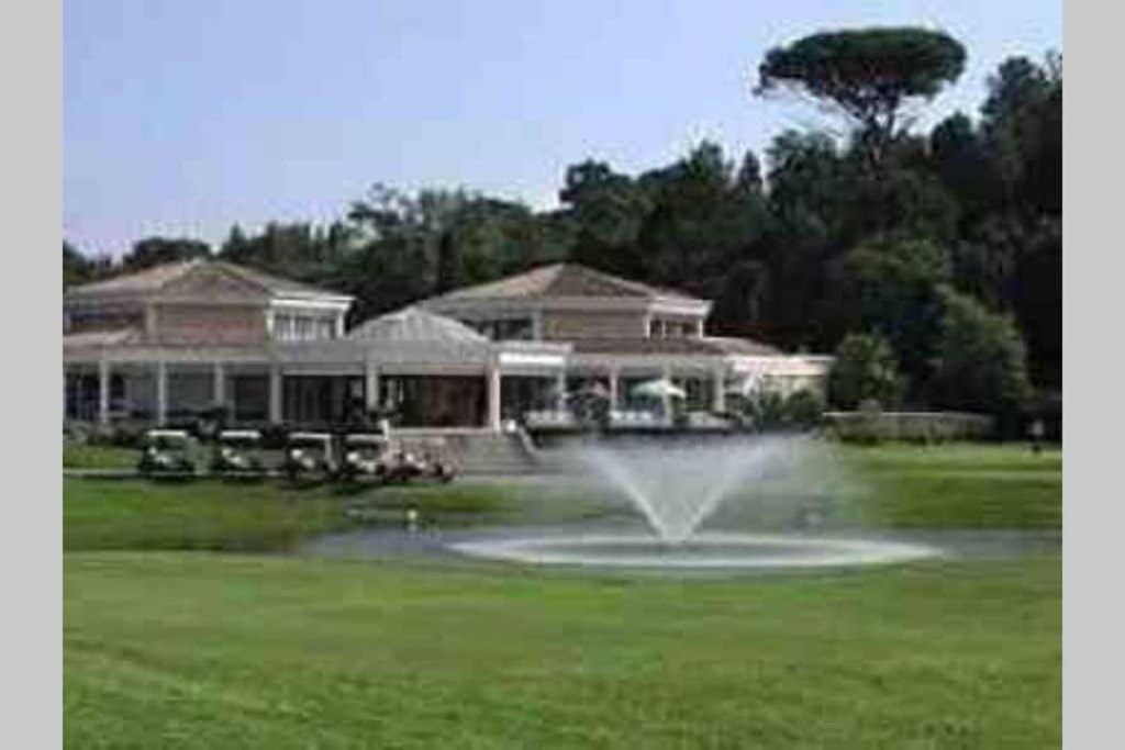 una fontana in mezzo a un prato di fronte a una casa di Riviera Golf de Barbossi Indiana a Mandelieu La Napoule