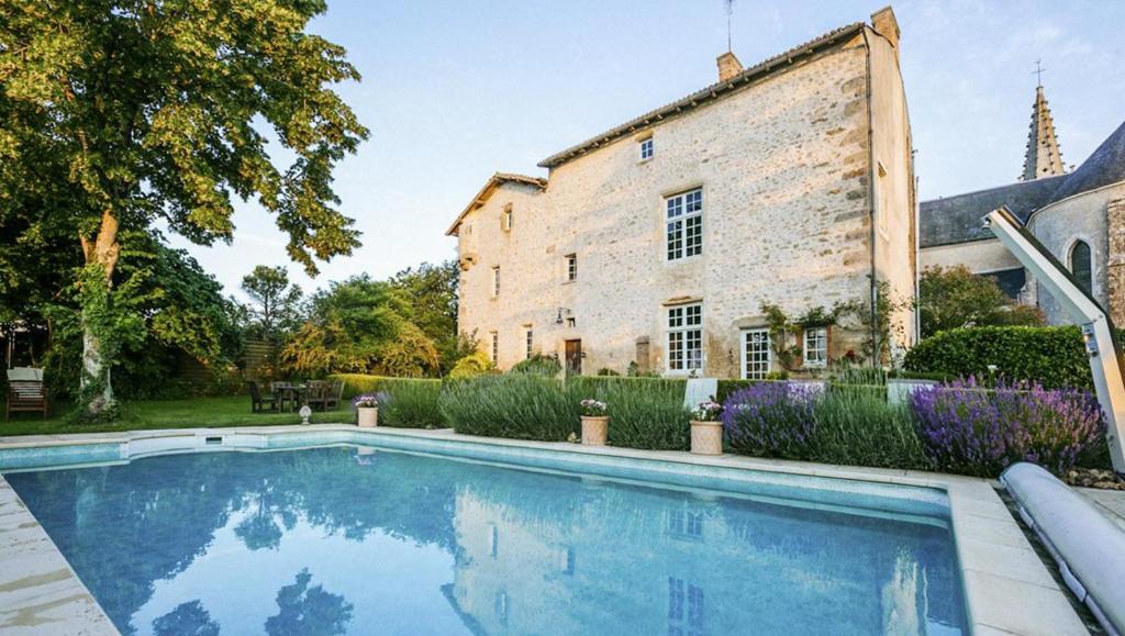 a house with a swimming pool in front of a building at 14th Century Priory in Pressigny in Pressigny