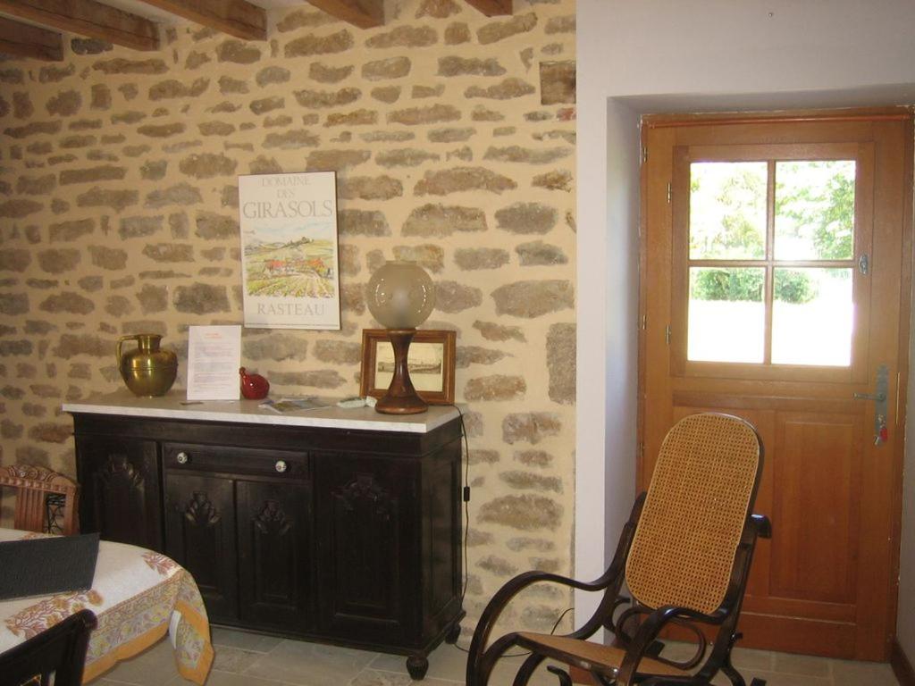 a room with a stone wall with a table and a chair at LA GRANGE in Saint-Prix-lès-Arnay